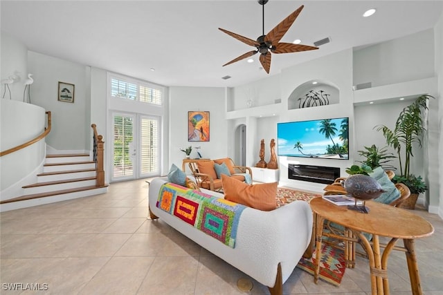 living area with recessed lighting, visible vents, stairway, a high ceiling, and a glass covered fireplace