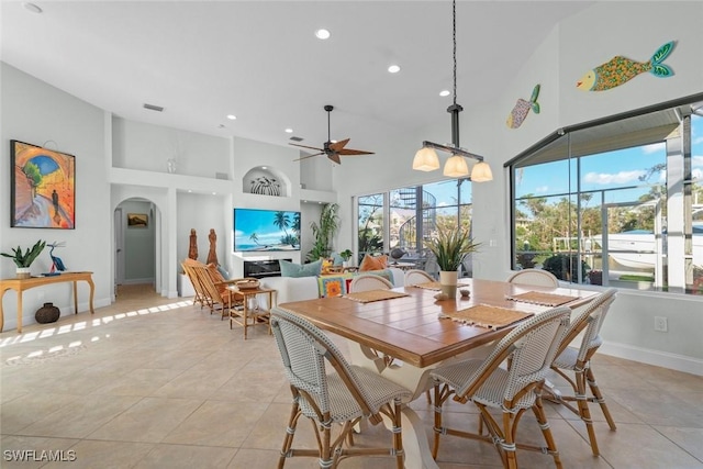 dining space with light tile patterned floors, baseboards, a high ceiling, and arched walkways