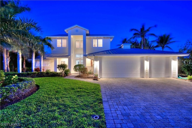 view of front facade featuring a garage, a yard, and decorative driveway