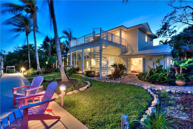 back of property with a balcony, metal roof, and a lawn