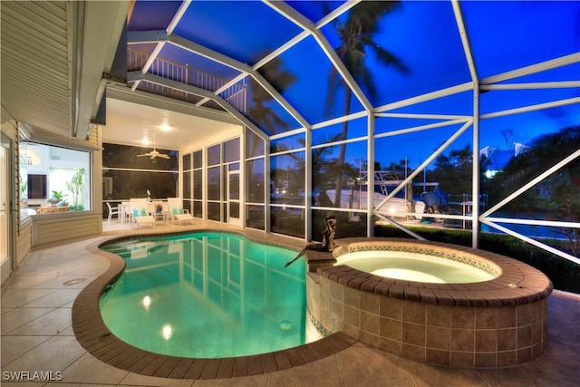 pool at night featuring a patio area, glass enclosure, and a pool with connected hot tub