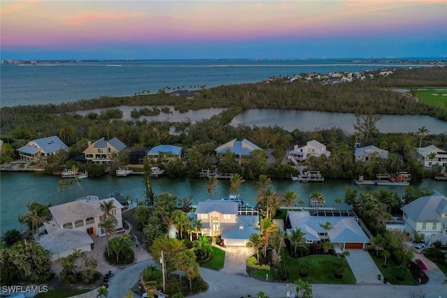 aerial view at dusk featuring a water view and a residential view