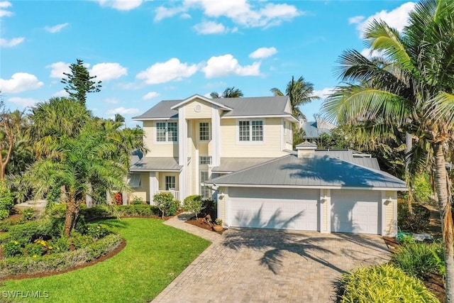 view of front of house featuring an attached garage, decorative driveway, and a front yard