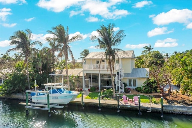 rear view of house with a water view, boat lift, and stairs