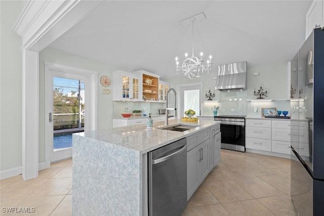 kitchen with white cabinets, wall chimney exhaust hood, glass insert cabinets, stainless steel appliances, and a sink