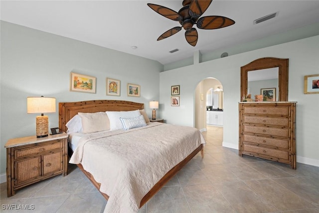 bedroom with arched walkways, visible vents, light tile patterned flooring, ensuite bath, and baseboards