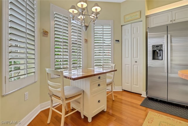 dining room with a chandelier, light wood-type flooring, and baseboards