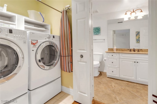 laundry area with light tile patterned flooring, laundry area, a sink, baseboards, and washer and dryer