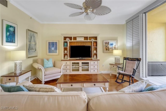 living area with baseboards, visible vents, a ceiling fan, ornamental molding, and wood finished floors