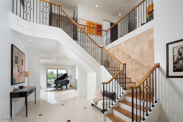 staircase featuring ornamental molding, recessed lighting, and a towering ceiling