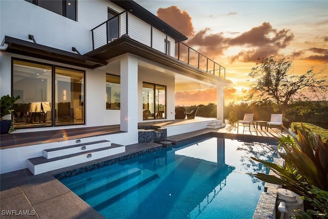 pool at dusk featuring a patio area and an outdoor pool