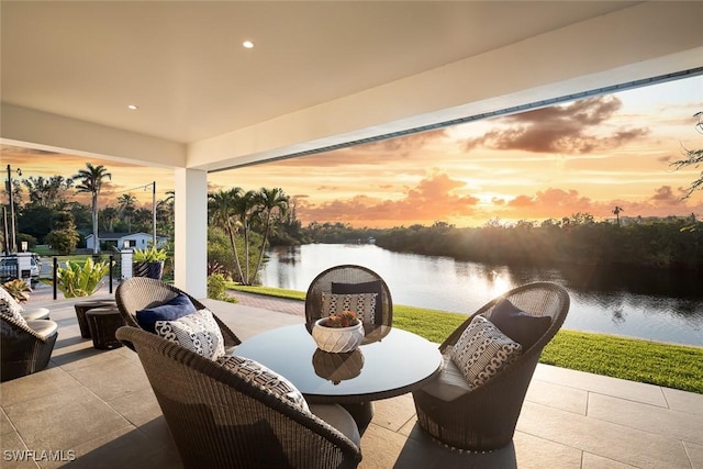 patio terrace at dusk featuring a water view