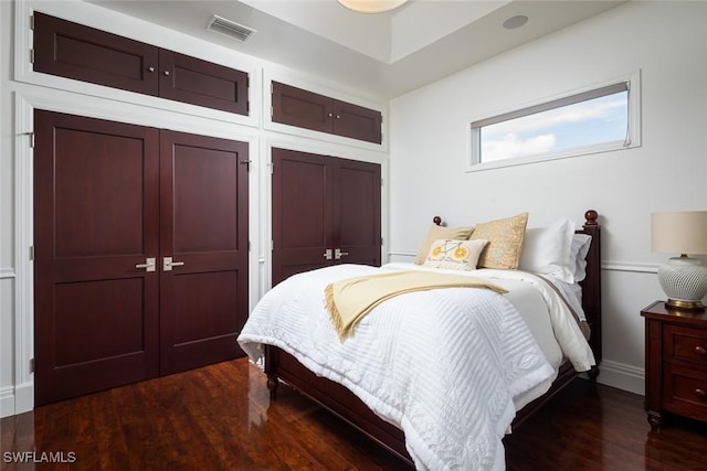 bedroom with dark wood-style floors and visible vents