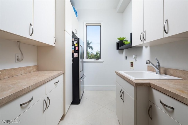 kitchen with freestanding refrigerator, light countertops, a sink, and white cabinetry