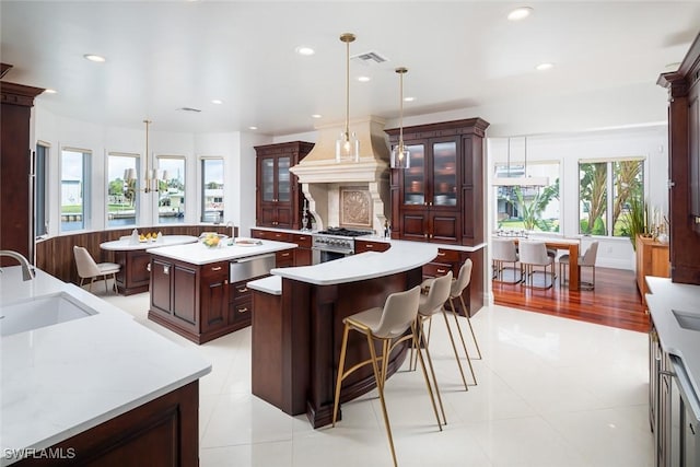 kitchen with light countertops, stainless steel range, a sink, and a kitchen island with sink