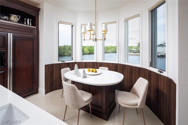 dining area featuring a chandelier, light tile patterned flooring, and a water view