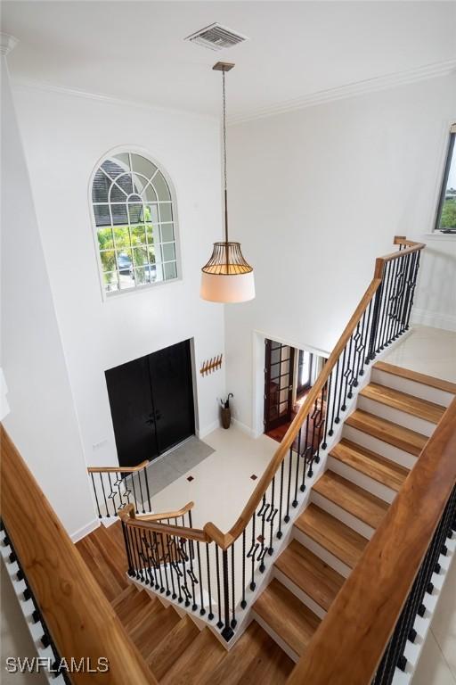 stairs featuring visible vents, crown molding, baseboards, and wood finished floors