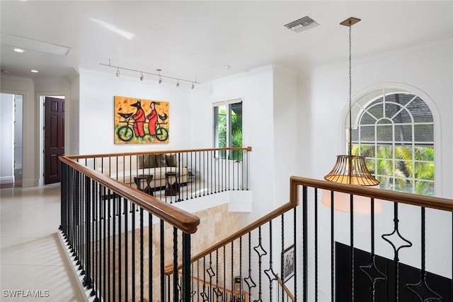 hall with rail lighting, an upstairs landing, visible vents, and crown molding