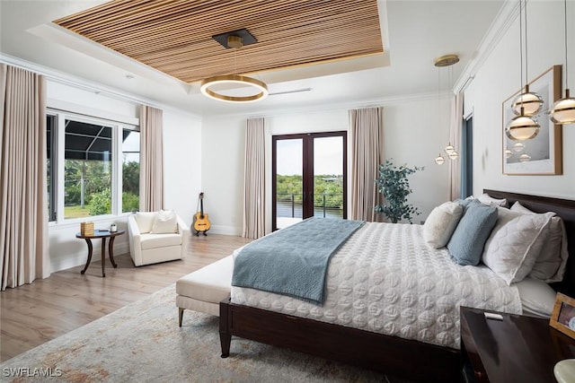 bedroom featuring a tray ceiling, french doors, multiple windows, and light wood finished floors