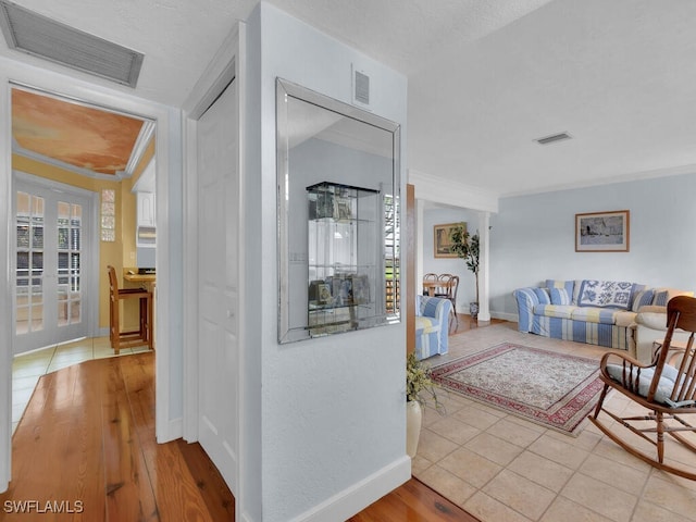 hall with a wealth of natural light, visible vents, and crown molding