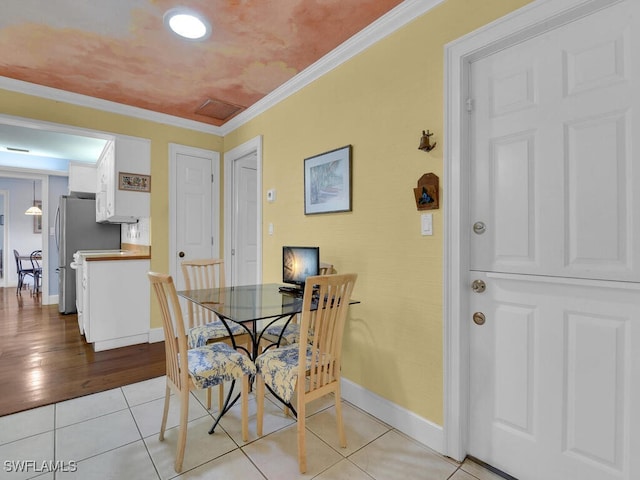 dining room featuring light tile patterned floors, baseboards, and ornamental molding