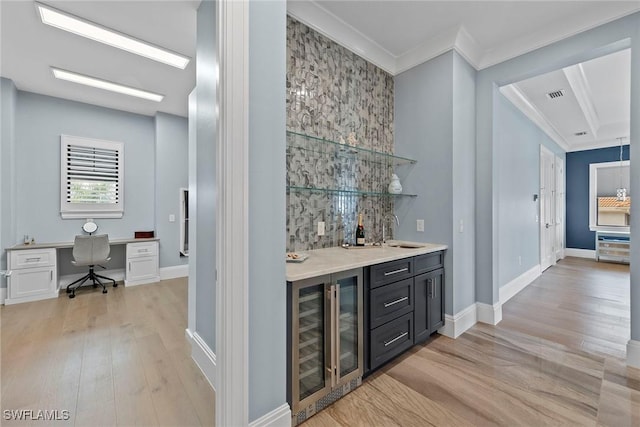 bar with beverage cooler, light wood-style flooring, indoor wet bar, and a sink