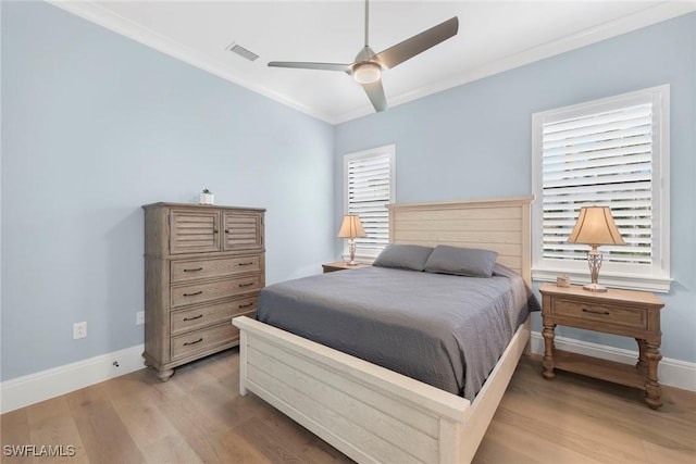 bedroom with light wood finished floors, visible vents, baseboards, and ornamental molding