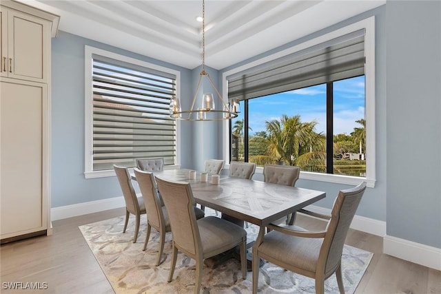 dining area featuring light wood-type flooring, baseboards, and a notable chandelier