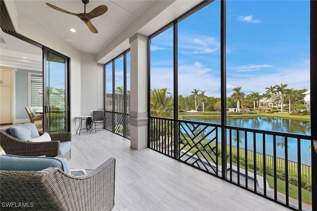 sunroom / solarium featuring ceiling fan and a water view