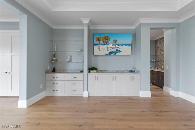 bar featuring baseboards, light wood-style flooring, and ornamental molding