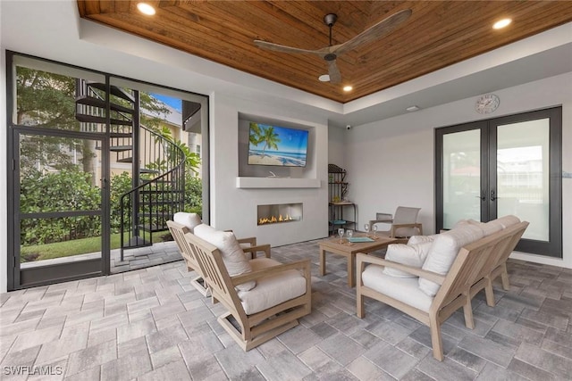 sitting room featuring wood ceiling, recessed lighting, french doors, a glass covered fireplace, and a raised ceiling