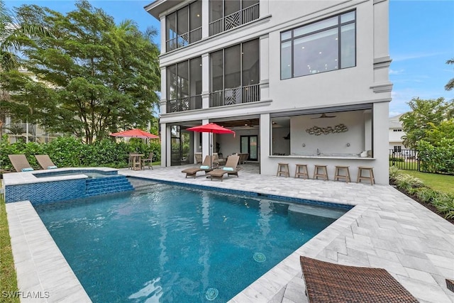 rear view of property with outdoor dry bar, stucco siding, a patio area, and fence