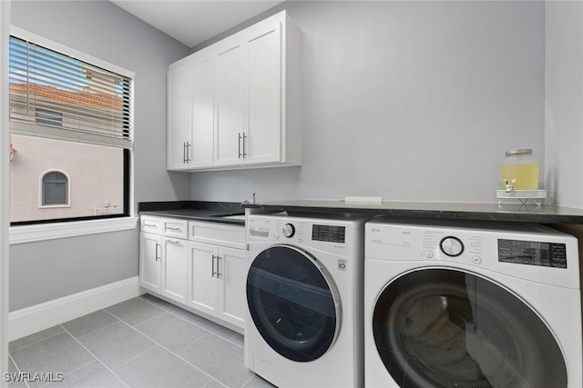 laundry area with washing machine and clothes dryer, light tile patterned floors, cabinet space, and baseboards