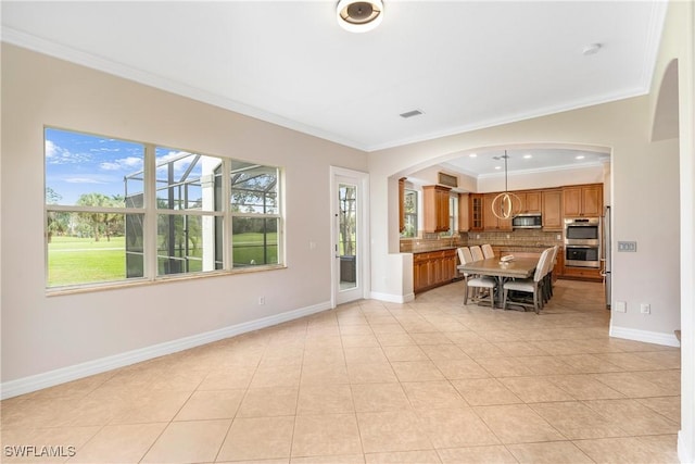 unfurnished living room featuring baseboards, plenty of natural light, visible vents, and crown molding