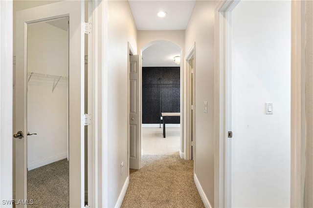 hallway with baseboards and light colored carpet