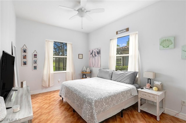 bedroom featuring ceiling fan, light wood-style floors, and baseboards