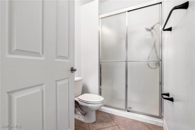 bathroom featuring a stall shower, tile patterned flooring, and toilet