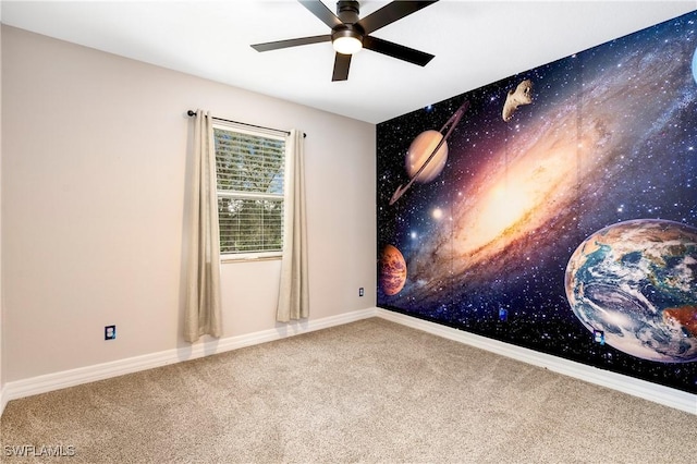 carpeted empty room with a ceiling fan and baseboards