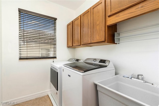 laundry area with cabinet space, baseboards, a sink, and washing machine and clothes dryer