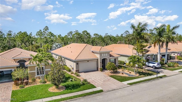 mediterranean / spanish-style home featuring a garage, stucco siding, decorative driveway, and a tiled roof