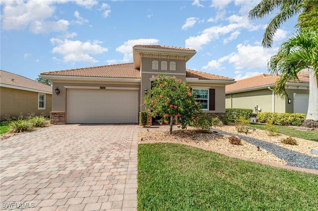 mediterranean / spanish-style house with a garage, a tiled roof, decorative driveway, and stucco siding