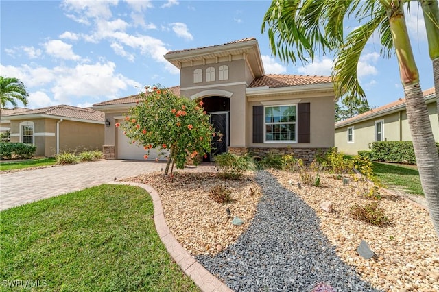 mediterranean / spanish house with an attached garage, stone siding, decorative driveway, and stucco siding