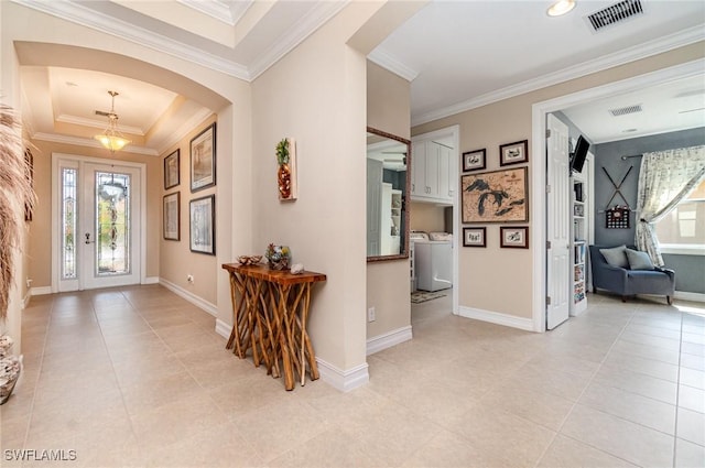 foyer entrance with arched walkways, a tray ceiling, visible vents, and crown molding