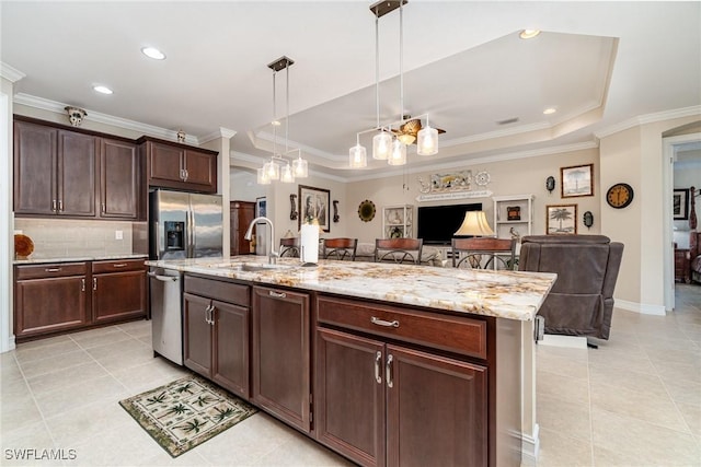 kitchen with stainless steel appliances, a raised ceiling, open floor plan, a kitchen island with sink, and dark brown cabinetry