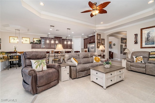 living room featuring recessed lighting, arched walkways, a raised ceiling, and ornamental molding