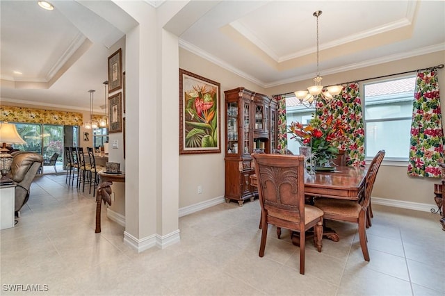 dining space with an inviting chandelier, baseboards, a tray ceiling, and ornamental molding