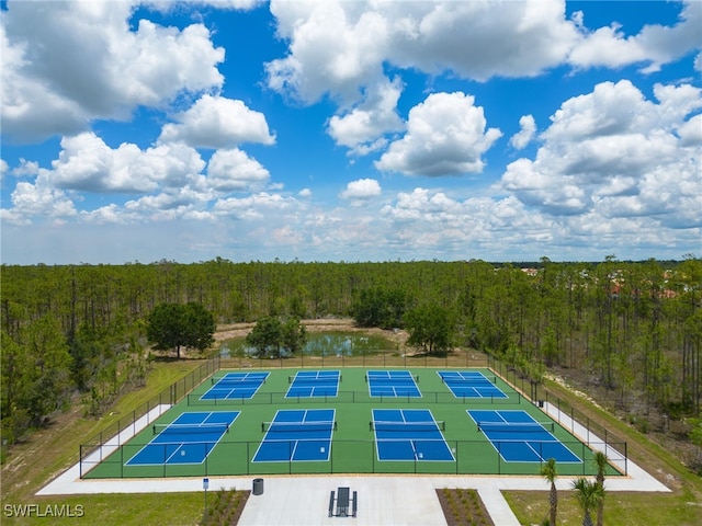 view of pool featuring a tennis court, a forest view, and fence