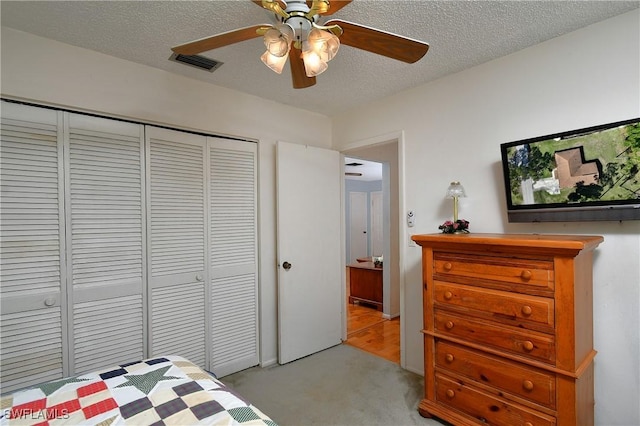 bedroom featuring a textured ceiling, light carpet, visible vents, a ceiling fan, and a closet