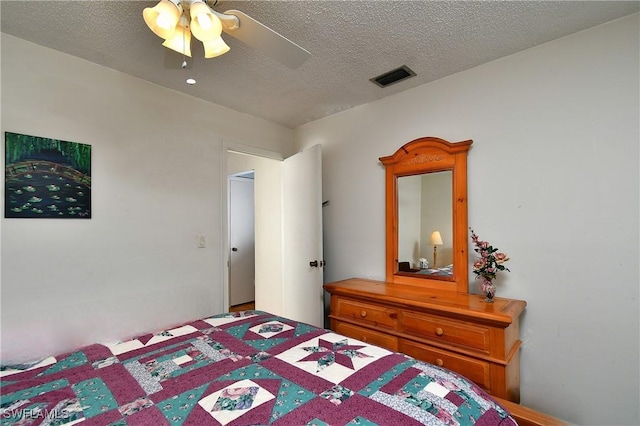 bedroom with a ceiling fan, visible vents, and a textured ceiling