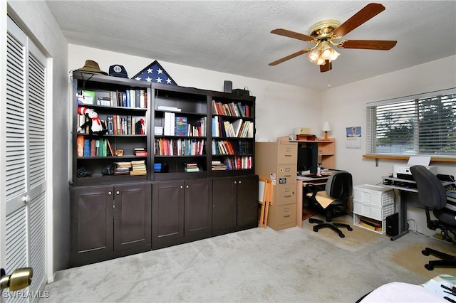 home office featuring a ceiling fan, light carpet, and a textured ceiling